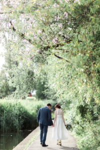 a bride and groom walking alongside the pond at Wylam Brewery