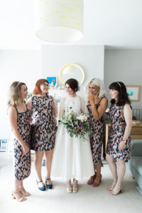 a photo of a bride and bridesmaids indoors in geometric patterned dresses